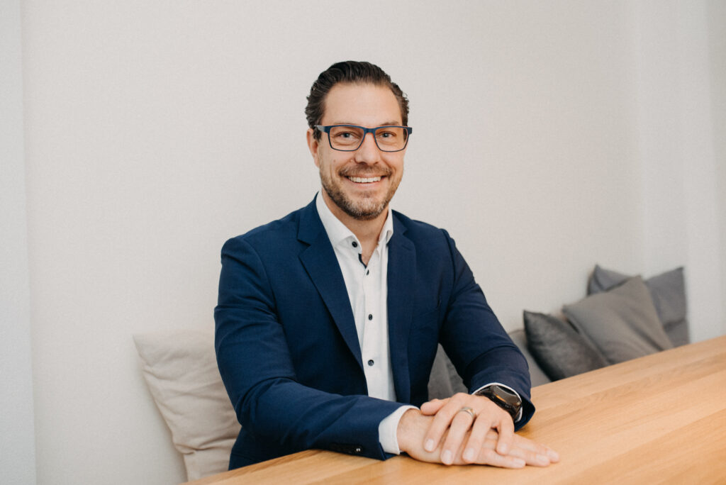 Business Coaching Freiburg - Portrait von Business Coach Patrik Schönberger – sitzend, mit freundlichem Blick und moderner Ausstrahlung, für Angebotsbereich der Website